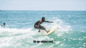 African surfer catches a wave with the caption "it is my religion now."